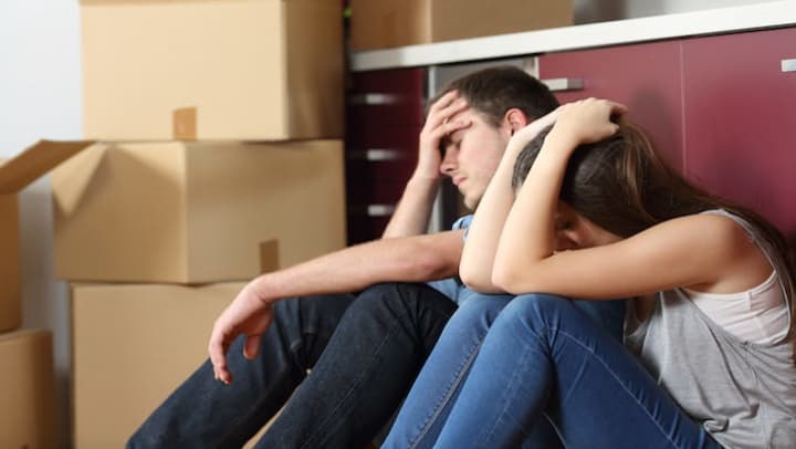 A stressed couple with moving boxes in the background.