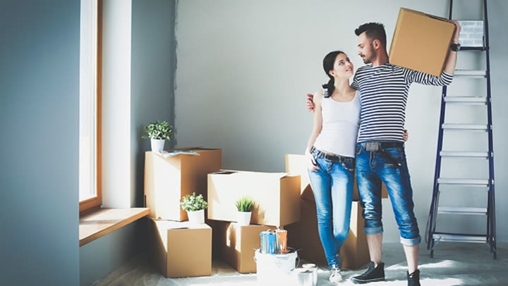 A young couple hugging in front of moving boxes.