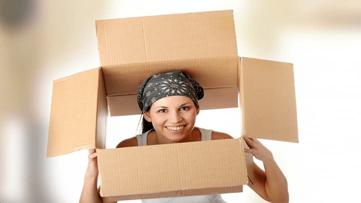 Smiling woman holding an open box over her head.