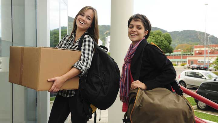 Two young women moving into a college dorm room.