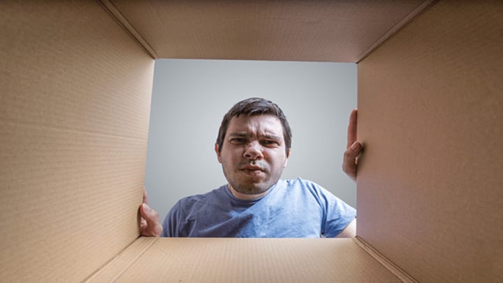 A confused man looking in a moving box.