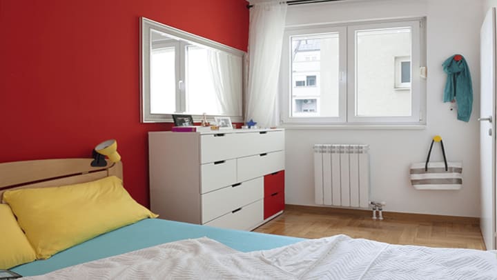 A red and white bedroom with a dresser.