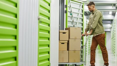 Man moving storage boxes into storage unit.