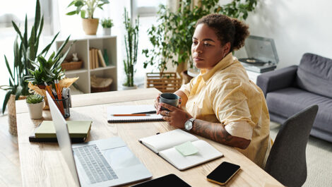 Woman working from home at her desk with laptop and coffee